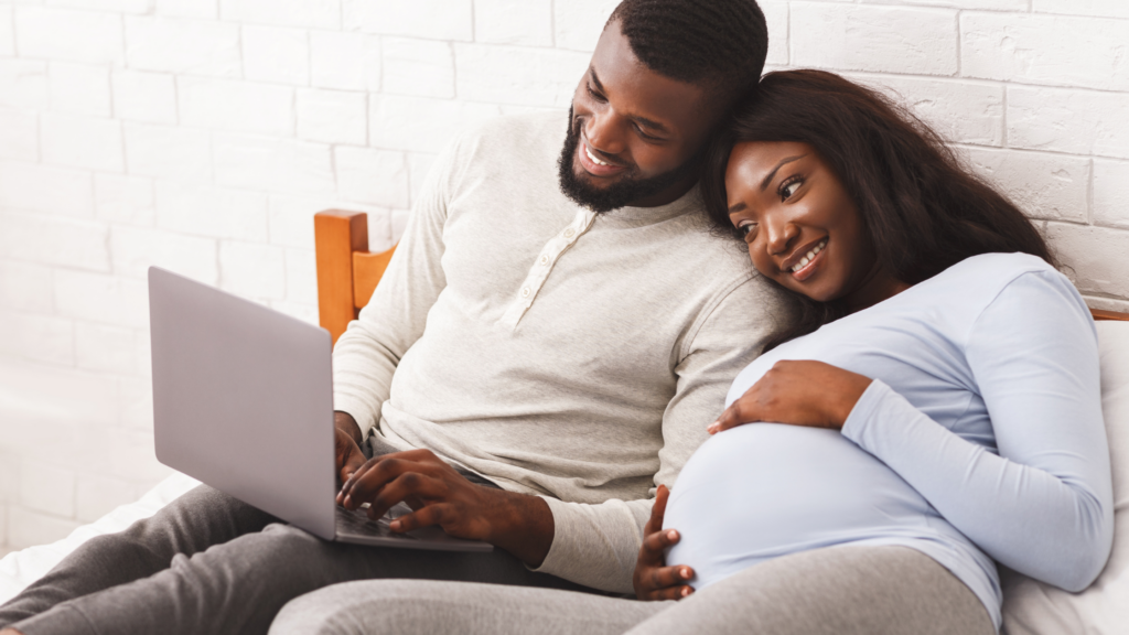 pregnant couple looking at a laptop