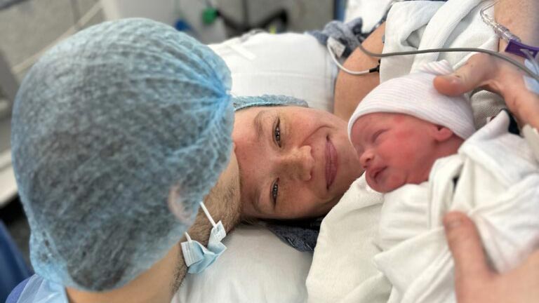 mom, dad and just born baby smiling in hospital bed